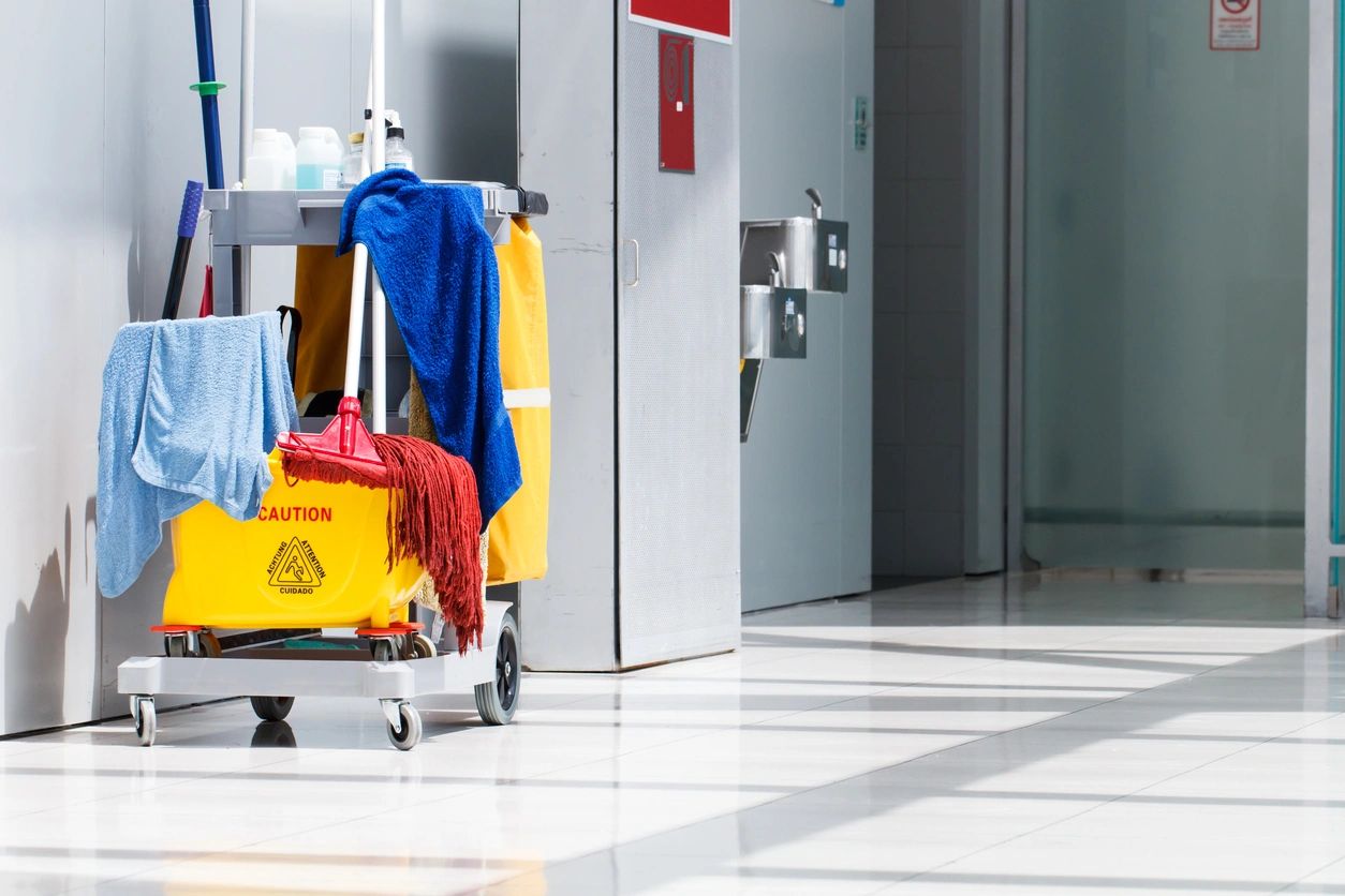 A cleaning cart with clothes on it in an airport.