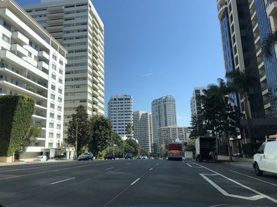 A street with tall buildings and cars on the side.